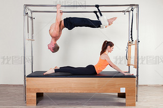 Pilates aerobic instructor woman and man in cadillac fitness exercise
