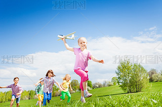 girl holds airplane with kids running