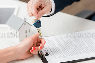 cropped view of realtor giving key to woman near carton house model, leasing concept