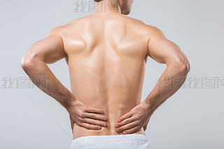 rear view of man hing back pain, isolated on grey 
