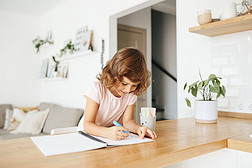 可爱而快乐的小女孩，可爱的学龄前儿童，5岁的孩子在家里的一个白色客厅的桌子上画画。家庭教育的概念
