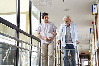 young asian physical therapist working with senior man on walking using a walker