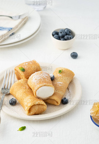 Crepes, thin pancakes with cream cheese and fresh blueberries.