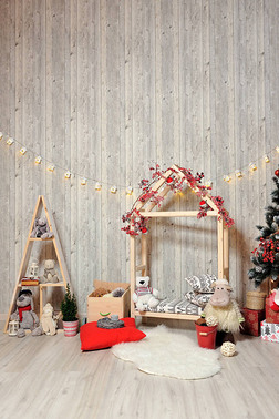 儿童新年或圣诞节照片区。 儿童摄影区，配有木制房屋、玩具、圣诞树和温暖光线下的礼物