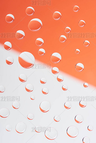 close-up view of transparent calm water drops on white and orange background          