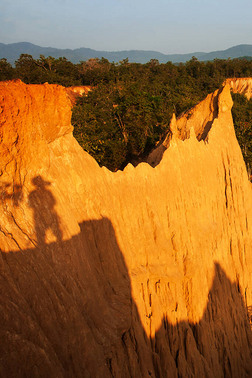 夏天黄昏的时候，原始森林里陡峭的橙色砂岩的神奇风景，一个摄影师在砂岩上的影子。Sao Din Na Noi，泰国.