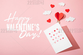 top view of greeting card with hearts near paper heart shaped air balloon in clouds and  happy valen