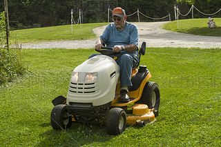 Senior Citizen Cutting Grass On A Riding Lawnmower