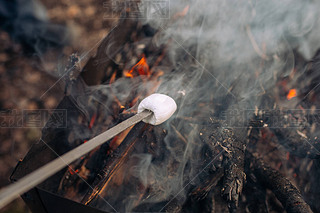 Marshmallow grilling on bonfire, oke and heat from fire