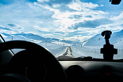 在雪地覆盖的山路上开车时，手扶方向盘。地面的浅水区。高质量的照片