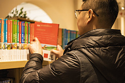 世界读书日广告海报背景素材男士在书架上拿起书集