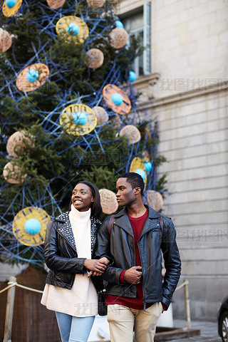 Laughing couple on christmas vacation walking in the city, beautiful young couple hing fun walking
