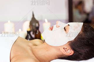 Prettyl woman with facial mask at beauty salon. Spa treatment