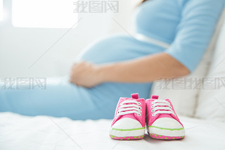 Baby Shoes with a pregnant woman on the background