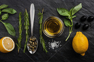 Herbs mix with  lemons , capers and olives on the black stone table