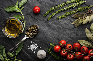 Herbs mix with tomatoes and olive oil on the black stone table