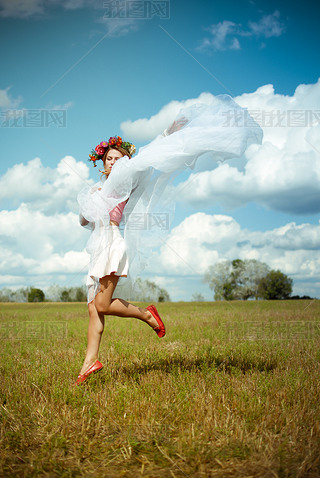 Girl in flower wreath with white shawl dancing on meadow