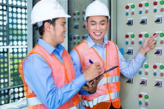 Asian technicians at panel on construction site