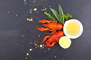 Delicious fresh lobster on dark vintage background. Seafood with aromatic herbs, spices and vegetabl