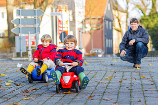 Two happy sibling boys and father playing with big old toy car, 