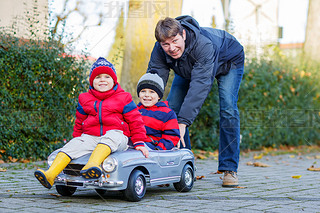Two happy sibling boys and father playing with big old toy car, 