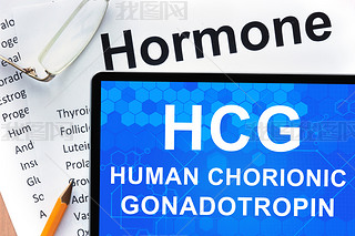 Papers with hormones list and tablet  with words  Human chorionic gonadotropin (HCG) .