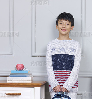 young asian boy iling standing beside book desk