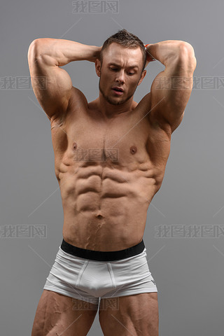 Shirtless athletic man posing over grey background in white underwear