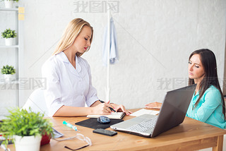 Doctor talking to patient in office, taking notes.