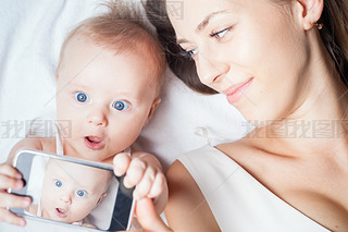 Funny baby girl with mom make selfie on mobile phone