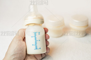 Father holding a baby bottle with breast milk with scale