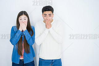 Beautiful young asian couple over white isolated background shocked covering mouth with hands for mi