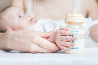 Baby holding a baby bottle with breast milk