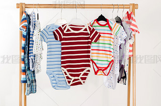 Dressing closet with clothes arranged on hangers.Colorful onesie of newborn,kids, toddlers, babies o
