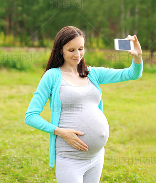 Happy young pregnant woman makes self-portrait on the artphone