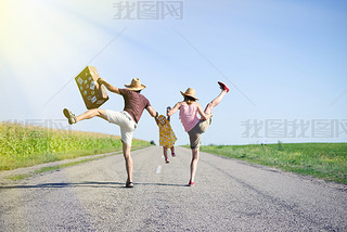 Happy family jumping and hing fun on road in summer