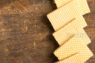 Closeup square cookies lying overlapping each other in a row across wooden surface