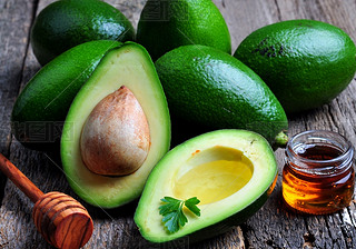 Fresh ocado with olive oil and honey on wooden background