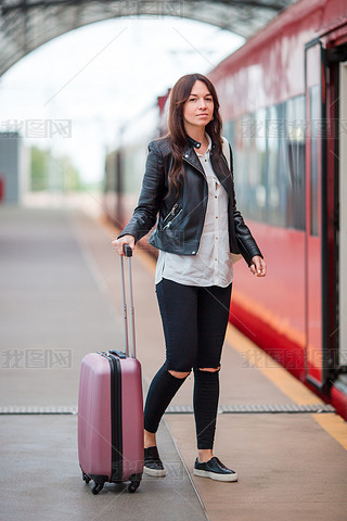 Young woman with luggage talking at train station. Caucasiam tourist waiting her express train while