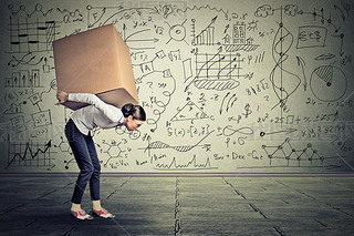 woman carrying hey box walking along gray wall 