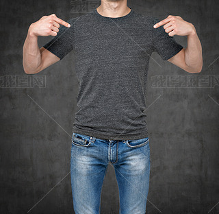 Close-up of a man pointing his fingers on a blank grey t-shirt. Dark concrete background.