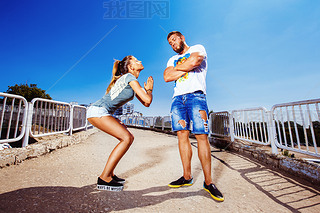 Young attractive girl is asking her man for forgiving making common gesture at summer bright backgro