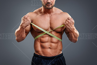 Bodybuilder measuring waist with tape measure