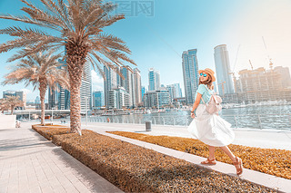 Happy asian girl walking on a promenade in Dubai Marina district. Trel and lifestyle in United Ara