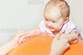 Mom with happy baby doing exercises at gymnastic ball