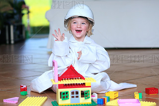 Toddler girl wearing safety helmet playing with building blocks