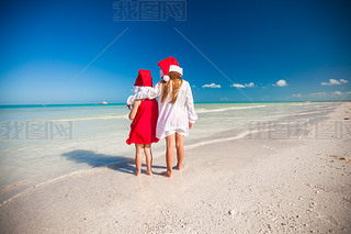 Two little cute girls?in Christmas hats he fun on the exotic beach