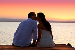 情侣接吻在日落坐在码头