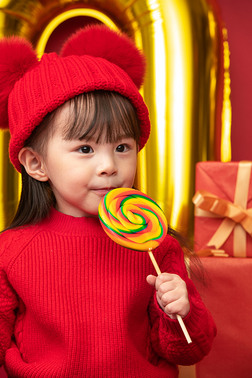新年棒棒糖摄影图|过新年的小女孩吃棒棒糖