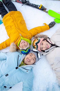 快乐的三口之家放松的躺在雪地上